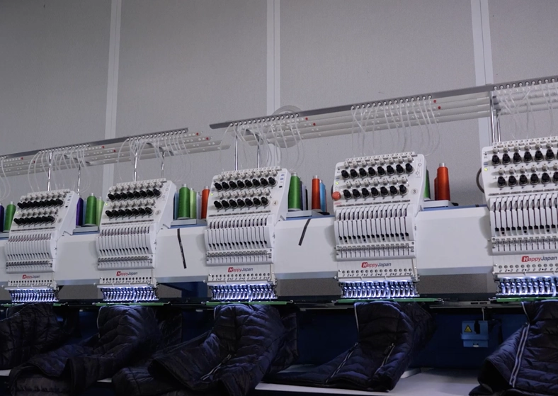 Machine à broder industrielle en action sur polo personnalisé — atelier Pen'Tee